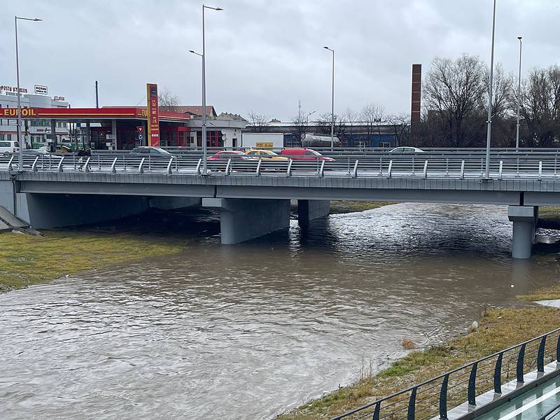 Râul Cibin cu debit crescut și apă tulbure, curgând pe sub un pod rutier din Sibiu