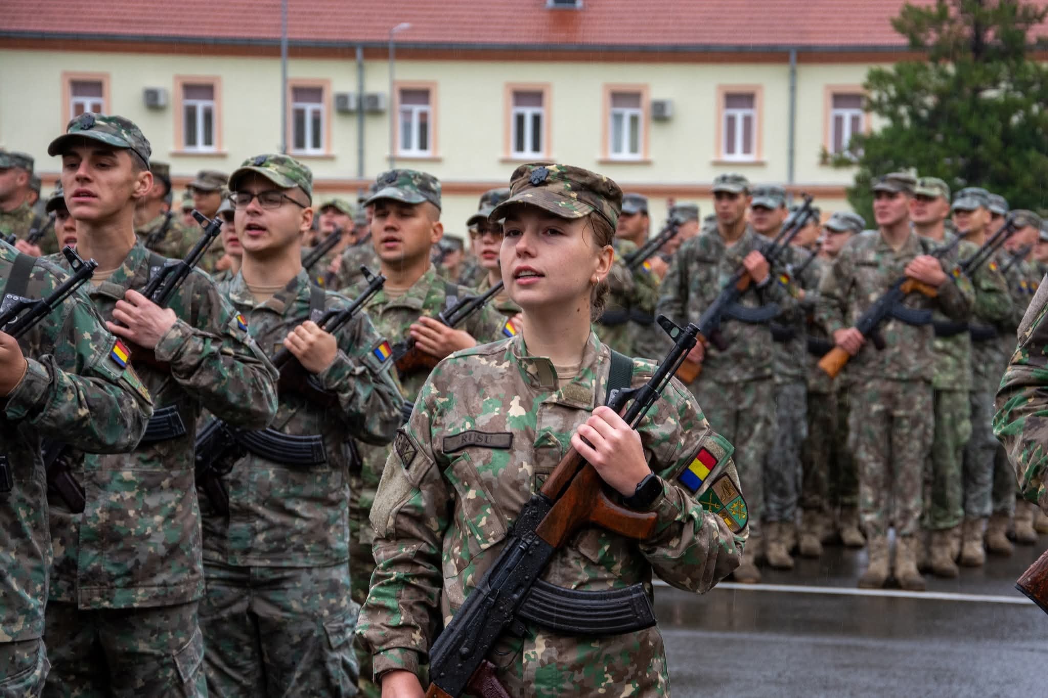 Solda militari în uniformă de camuflaj, participând la o paradă sau antrenament în Sibiu, România, în uniforme de camuflaj, simbolizând disciplina și patriotismul.