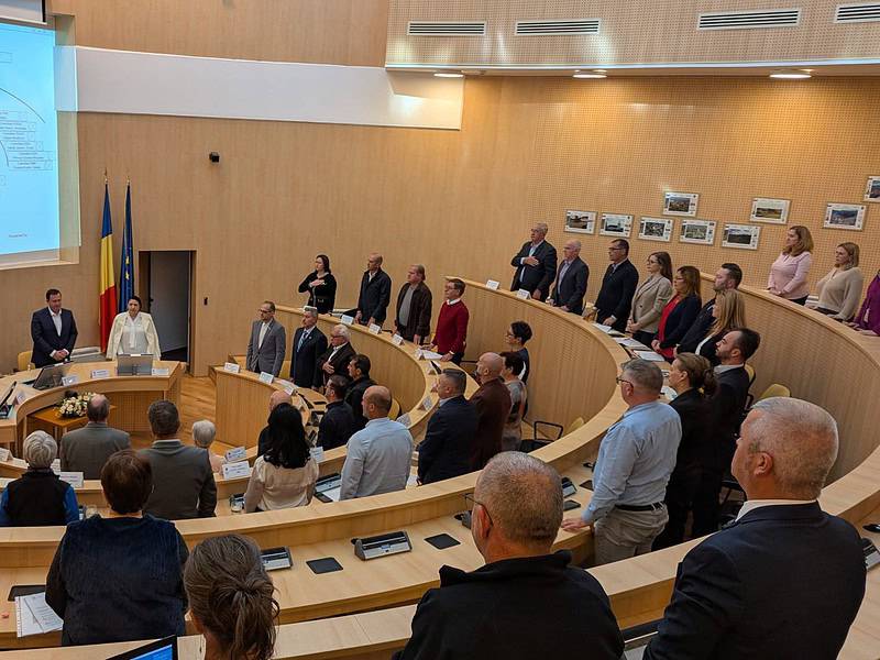 Consiliu local Sibiu, ședință de consiliu, oficiali în discuție, decor modern, imobil cu steaguri, imagine de la o întâlnire oficială, ora de Sibiu.