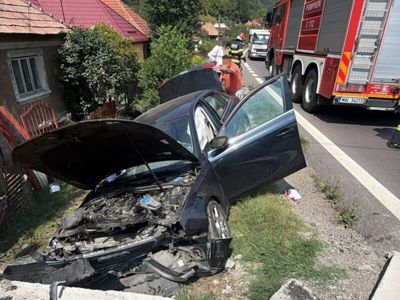 Autoturism cu partea din față distrusă după impactul cu un cap de pod pe DN7, lângă o autospecială de pompieri, la Robești