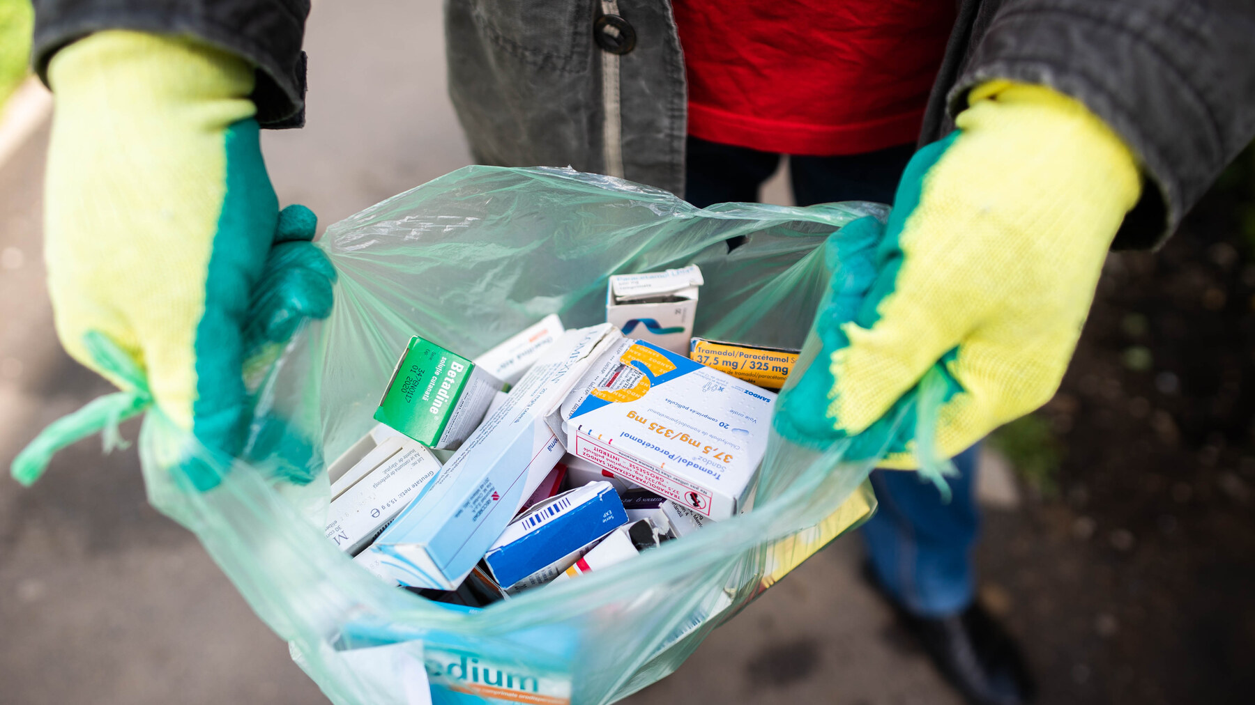 Mănuși de protecție țin o pungă cu medicamente vechi pentru colectarea deșeurilor periculoase