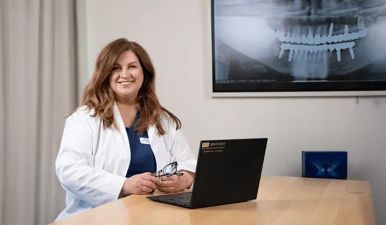 Dr. Ionela Dumitru, medic stomatolog specializat în implantologie, în cabinet, cu o radiografie dentară cu implanturi pe ecran