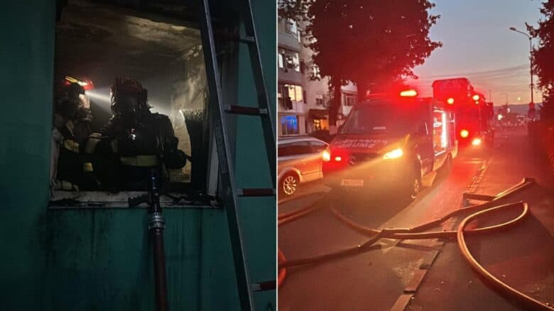 Pompieri ISU intervin la fereastra apartamentului incendiat din Sibiu; autospeciale de pompieri parcate pe stradă, cu furtunuri desfășurate