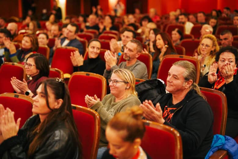 Spectatori aplaudând într-o sală de cinema cu scaune roșii la Astra Film Festival